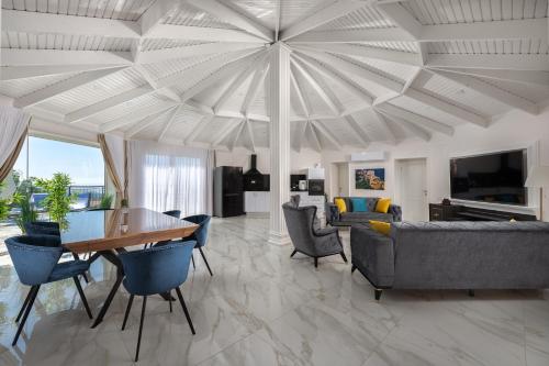a living room with a table and chairs at וילה מילגרוס - וילה עם בריכה פרטית מחוממת ומקורה - נוף לים in ‘Ein Ya‘aqov
