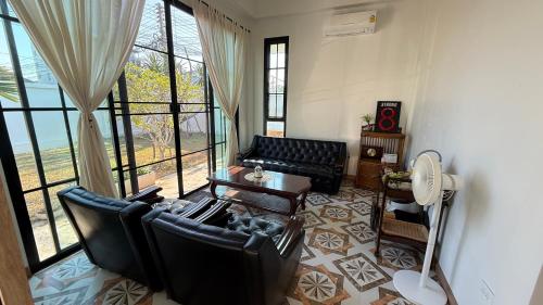 a living room with black leather chairs and a table at No 5 Home in Ratchaburi