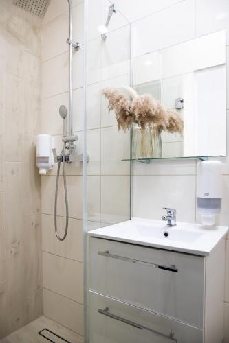 a bathroom with a sink and a shower with a mirror at ADLER Room Suite in Łódź