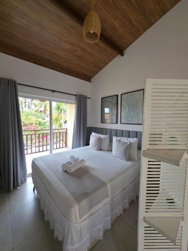 a bedroom with a large white bed and a balcony at Solar Águas Pipa Stays in Pipa