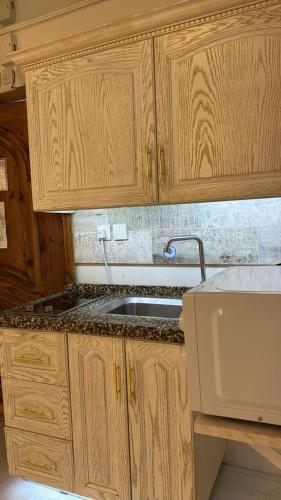 a kitchen with wooden cabinets and a sink at Rox Luxury Hotel - روكس الفاخرة in Taif