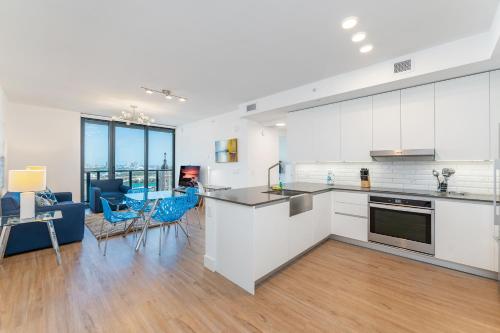 a kitchen and living room with white cabinets and blue chairs at Global Luxury Suites Miami Worldcenter in Miami