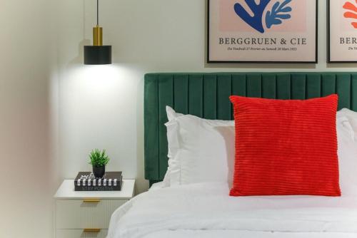a red pillow on a bed with a green headboard at LUX Studio King Bed Free Parking Gym New in Pittsburgh