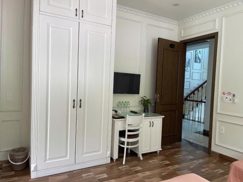 Lynh's Villa في كات با: غرفة بيضاء مع مكتب وطاولة