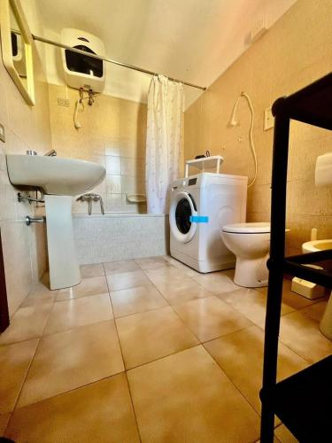 a bathroom with a toilet sink and a washing machine at Casa Lucia in Villasimius