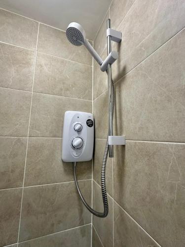 a shower with a shower head in a bathroom at Kettering Railway Lodge in Kettering