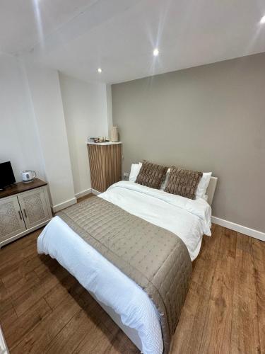 a bedroom with a large bed and a wooden floor at Kettering Railway Lodge in Kettering