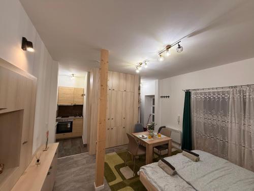 a room with a bed and a table and a kitchen at Infinity Apartman in Esztergom