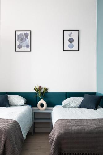 a bedroom with two beds and a vase on a table at ADLER Room Suite in Łódź