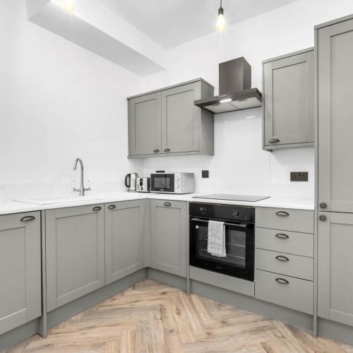 a kitchen with white cabinets and a stove top oven at Central Wolverhampton 2-Bed Townhouse - Gated & Secure - Bedroom TV 1CO in Wolverhampton