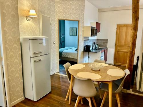 een kleine keuken met een tafel en een kamer met een bed bij La Grande escapade T12 in Troyes