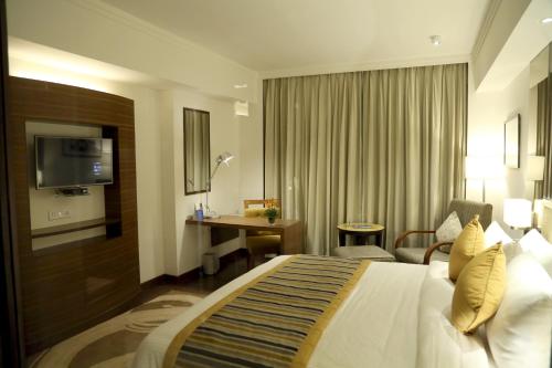 a hotel room with a bed and a desk at Aditya Park-A Sarovar Portico Hotel in Hyderabad