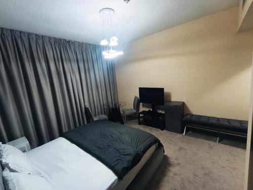 アジュマーンにあるApartHotel Roomsのベッドと机とテレビのある寝室