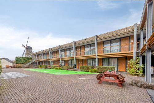 a building with a bench and a windmill in the background at Hotel Beneden Leeuwen in Beneden-Leeuwen