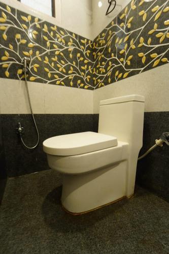 a white toilet in a bathroom with a painting on the wall at Sharsh Banquet and Hotel in Patna