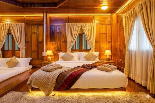 a bedroom with two beds and two windows at Wellness Resort Rayong Managed by the SCN in Ban Huai Pla Kang