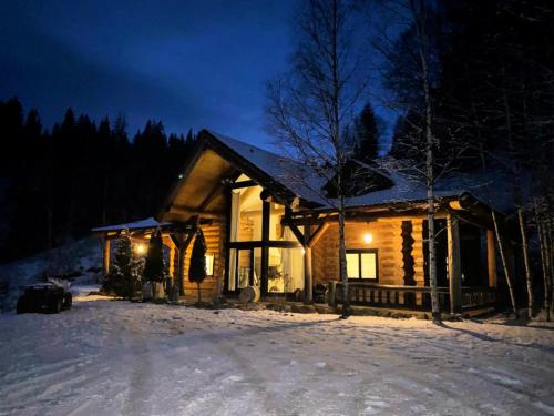 a log cabin in the snow at night at Mi Chalet - Poiana Izvoarelor in Vatra Dornei