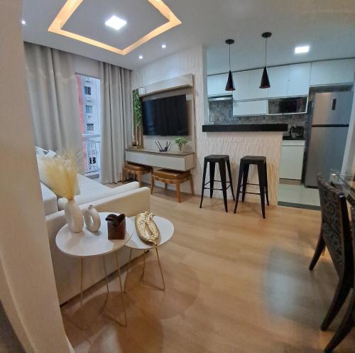 een woonkamer met een witte bank en een keuken bij Riocentro, Projac, Parque Olímpico, apartamento completo com vaga! in Rio de Janeiro