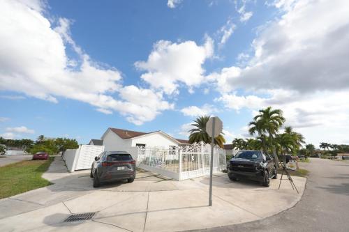 two cars parked in a parking lot in front of a house at E&A SouthWest Miami - Breeze Studio in Kendale Lakes