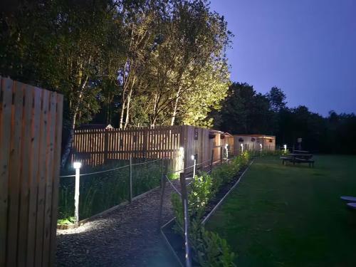 a garden with a fence and a picnic table at night at The Forest Pod - Wood Fired Hot Tub and Fire Pit in Hambleton
