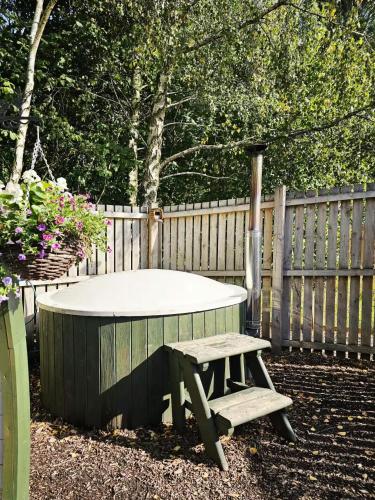 a picnic table and bench next to a fence at The Forest Pod - Wood Fired Hot Tub and Fire Pit in Hambleton