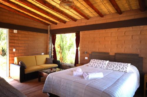 een slaapkamer met een bed en een bank in een kamer bij Cabañas Los Cardones Tilcara in Tilcara