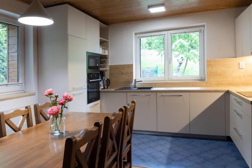 a kitchen with a wooden table with a vase of flowers at Chata pod Prašivou in Vyšní Lhoty