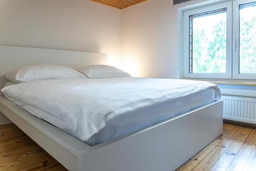 a white bed in a white bedroom with a window at Chata pod Prašivou in Vyšní Lhoty