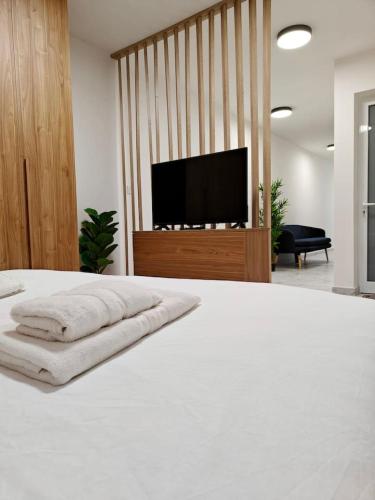 een slaapkamer met een wit bed en een flatscreen-tv bij Balluta Bliss in Il-Gżira
