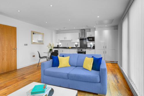 a living room with a blue couch and a kitchen at Hybrid Resi - London, Greenwich near O2 Arena in London