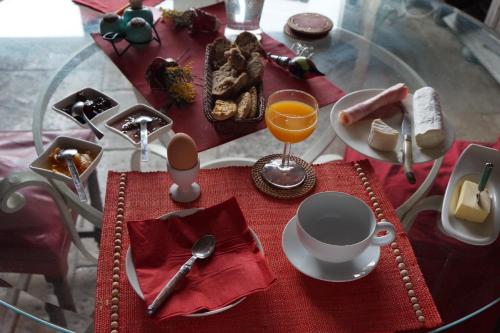 una mesa de cristal con un mantel rojo con comida y bebida en La Grille Fleurie, chambre d'hôte chez l'habitant, en Arthonnay