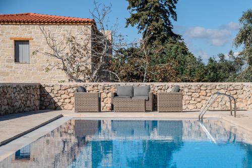 a villa with a swimming pool and a stone wall at Vamos villa in Vamos