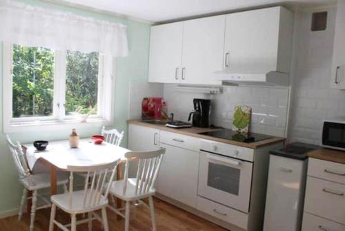 Two cottages by the forest & sea SE09136 في Slussen: مطبخ مع طاولة وكراسي ومطبخ مع دواليب بيضاء