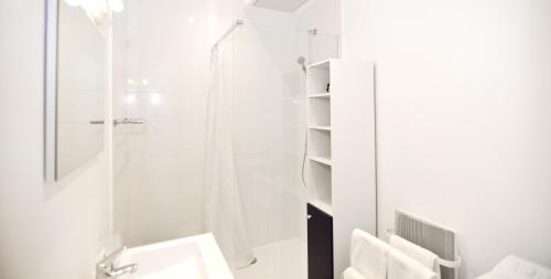 a white bathroom with a shower and a sink at Appart' Rousseau in Lyon