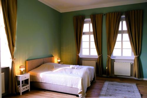 een groene slaapkamer met een bed en 2 ramen bij Hofensemble nahe Berlin in Lietzen