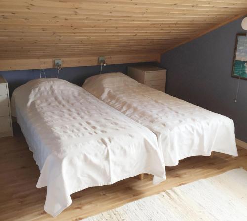 Lovely Cottage near the Resort Nösund SE09111 في Tegneby: سريرين مع شراشف بيضاء في الغرفة