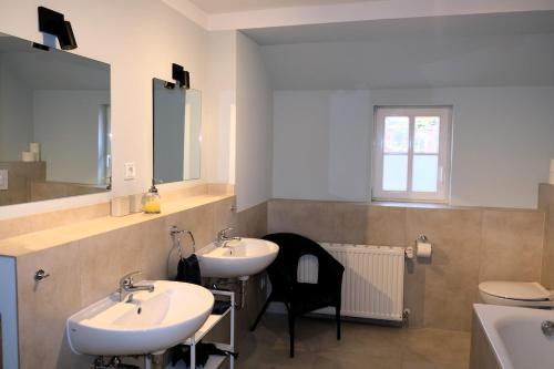 een badkamer met 2 wastafels en een stoel. bij Hofensemble nahe Berlin in Lietzen