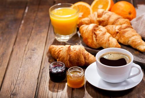 a table with a cup of coffee and croissants and orange juice at Amenano Luxury in Catania
