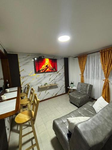 Apartamento cerca al aeropuerto في بوغوتا: غرفة معيشة مع أريكة وتلفزيون على الحائط