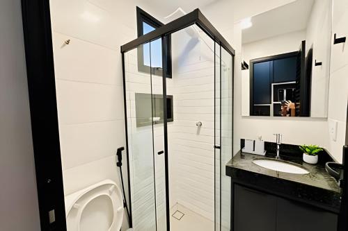 um banheiro com vaso sanitário, pia e espelho em Studio Ônix - A poucos passos da Ufu. em Uberlândia