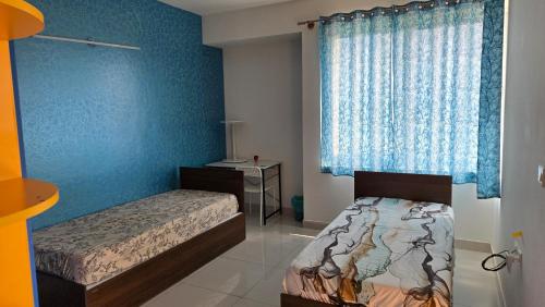 ein Schlafzimmer mit zwei Betten und einer blauen Wand in der Unterkunft Hoysala Ace 1 in Bangalore