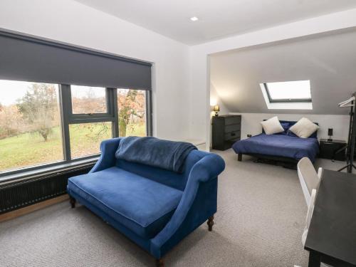 een slaapkamer met een blauwe bank, een bed en een raam bij Chapel Hill in Penton