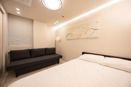 a bedroom with a bed and a black couch at 율 한옥 호텔 in Samgong