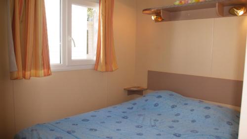 a bedroom with a bed and a window at Camping Tikayan La Célestine - Maeva in Beynes