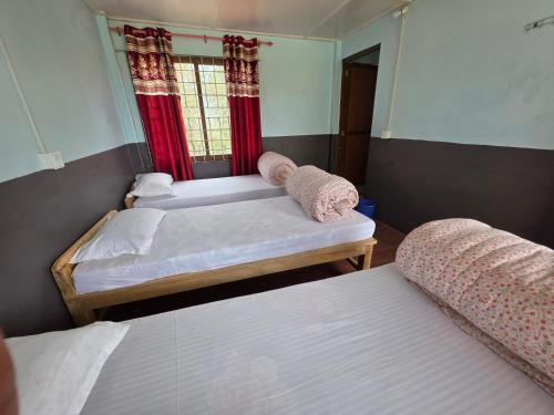 two beds in a room with red curtains at Hotel mardi station in Astam