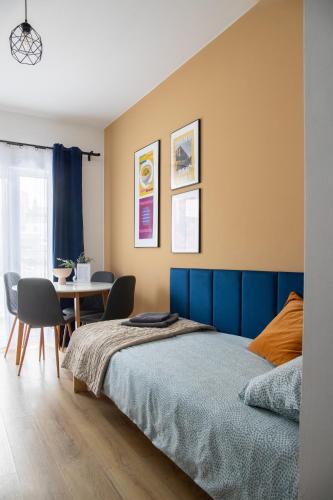 a bedroom with a blue bed and a table at ADLER Apartments in Łódź