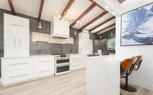 Una cocina con gabinetes blancos y un cuadro grande en la pared. en Charming Four-Bedroom Coastal Retreat Near Neptune Beach, en Neptune Beach