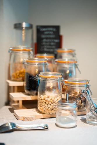 Un grupo de frascos llenos de comida sobre una mesa. en Hôtel Restaurant Le Madame, en La Ferrière