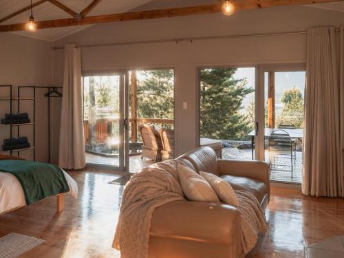 a living room with a leather couch and sliding glass doors at Barn Owl Cabin at Vrolikheid Landgoed in Tulbagh