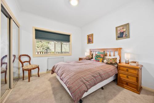 a bedroom with a bed and a chair and a window at Maureens Retreat in Eureka